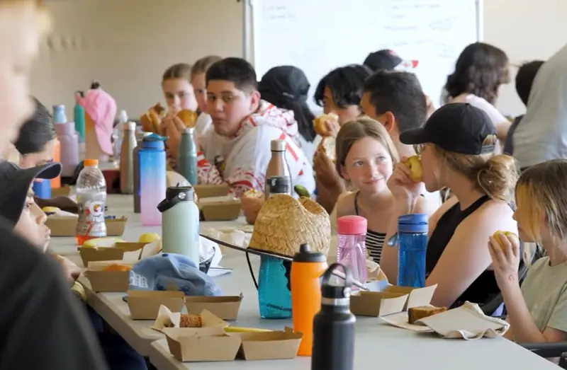 Campers share lunch together at the long dining tables