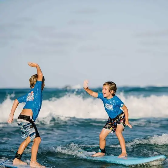 Two young students ride their first whitewater wave side by side
