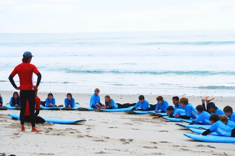 An instructor talks a class through the session as students lie ready on their boards