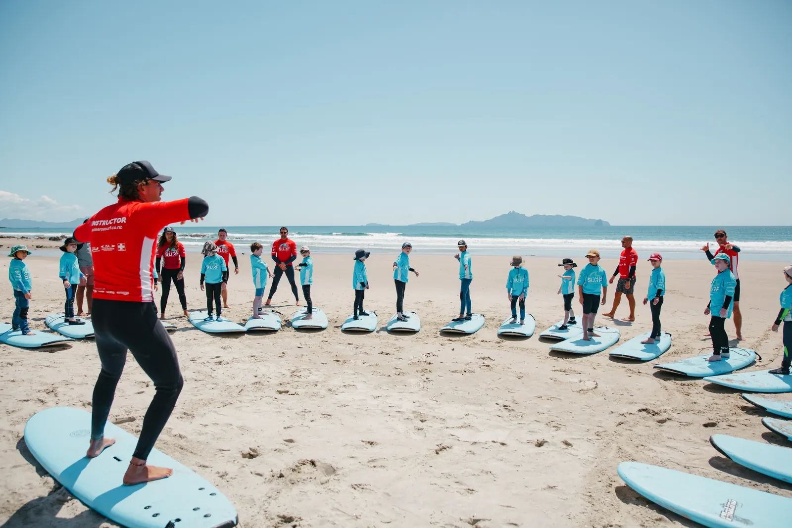 A class practises pop-ups on the beach as an instructor demonstrates